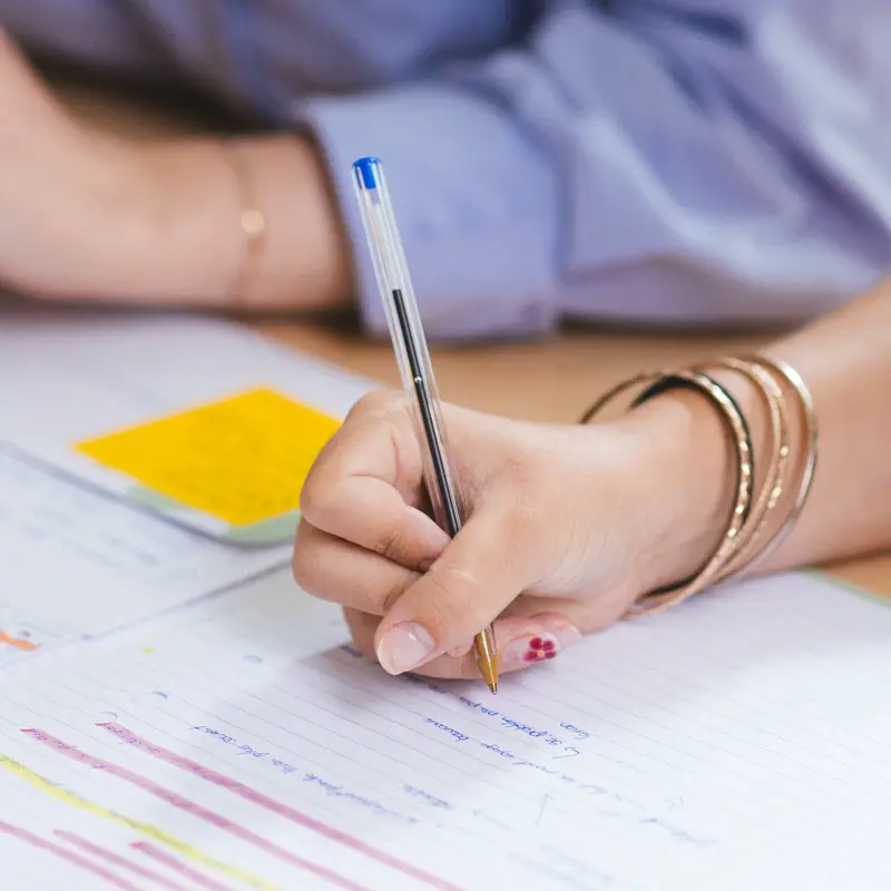 Gros plan sur la main d’une élève écrivant dans son cahier