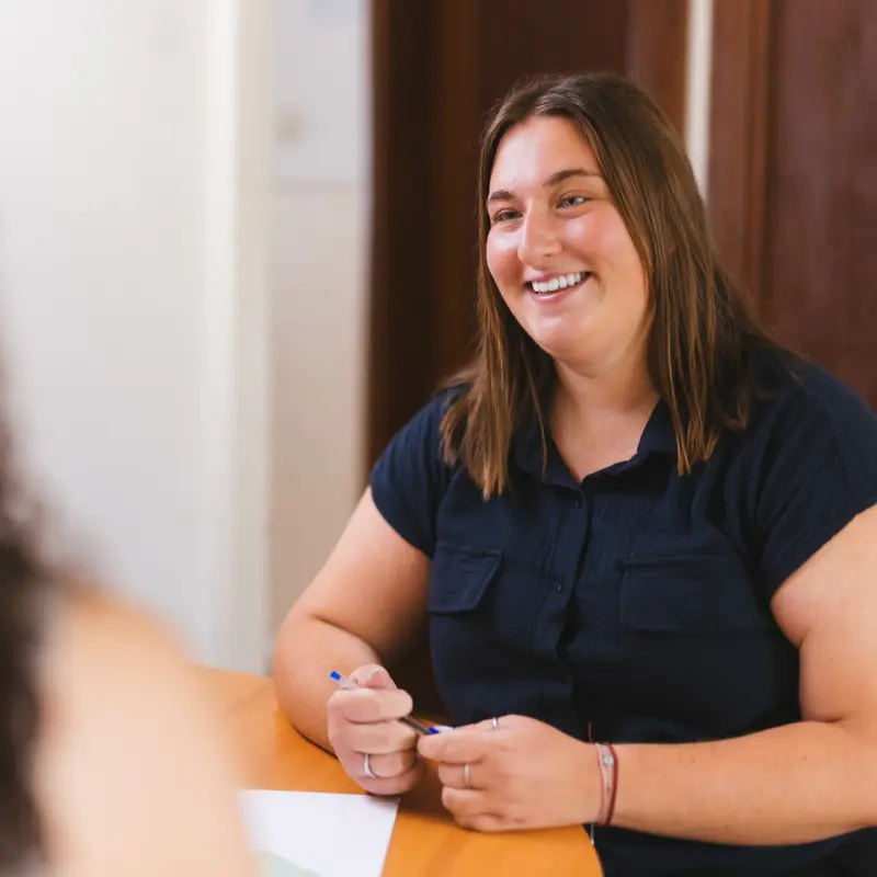 The trainer's colleague, smiling at her desk